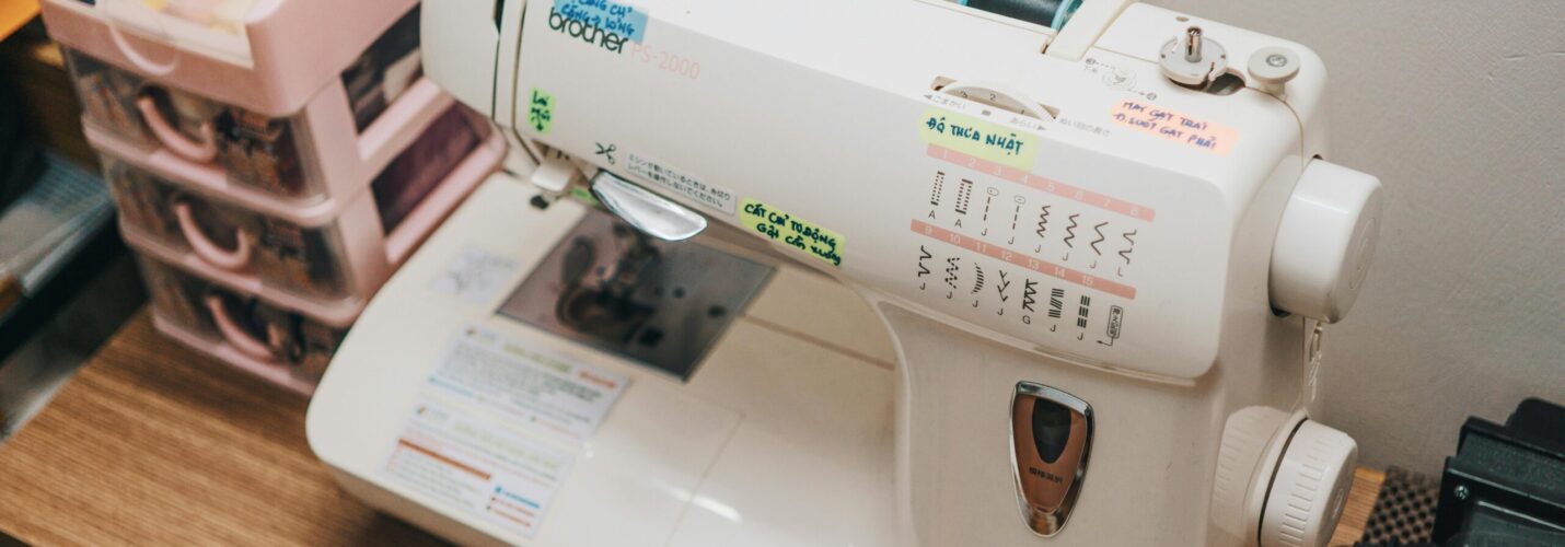 Dikiş makinesi üzerinde iplik yönü, iğne kaldırma, geri dikiş ve dikiş ayar sembolleri ile kullanım rehberi.